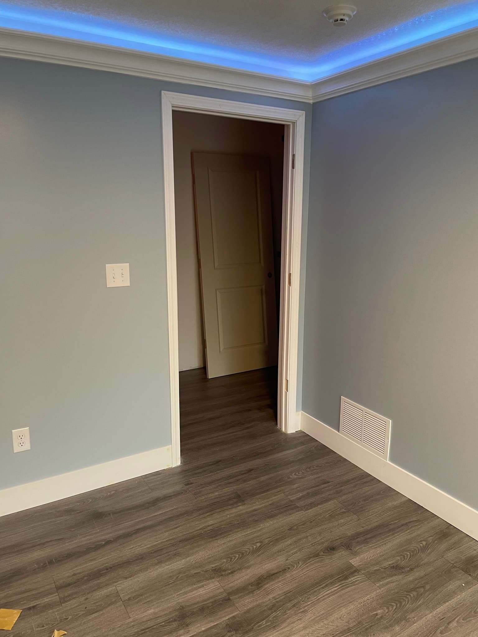 Room with blue accent ceiling lighting and dark wood flooring