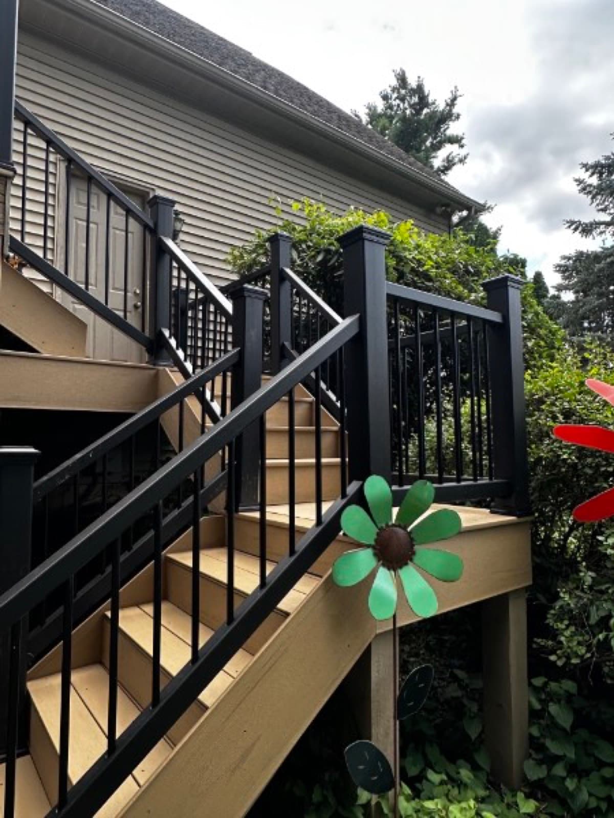 Angled view of stacked composite deck landings with black railings against tan siding