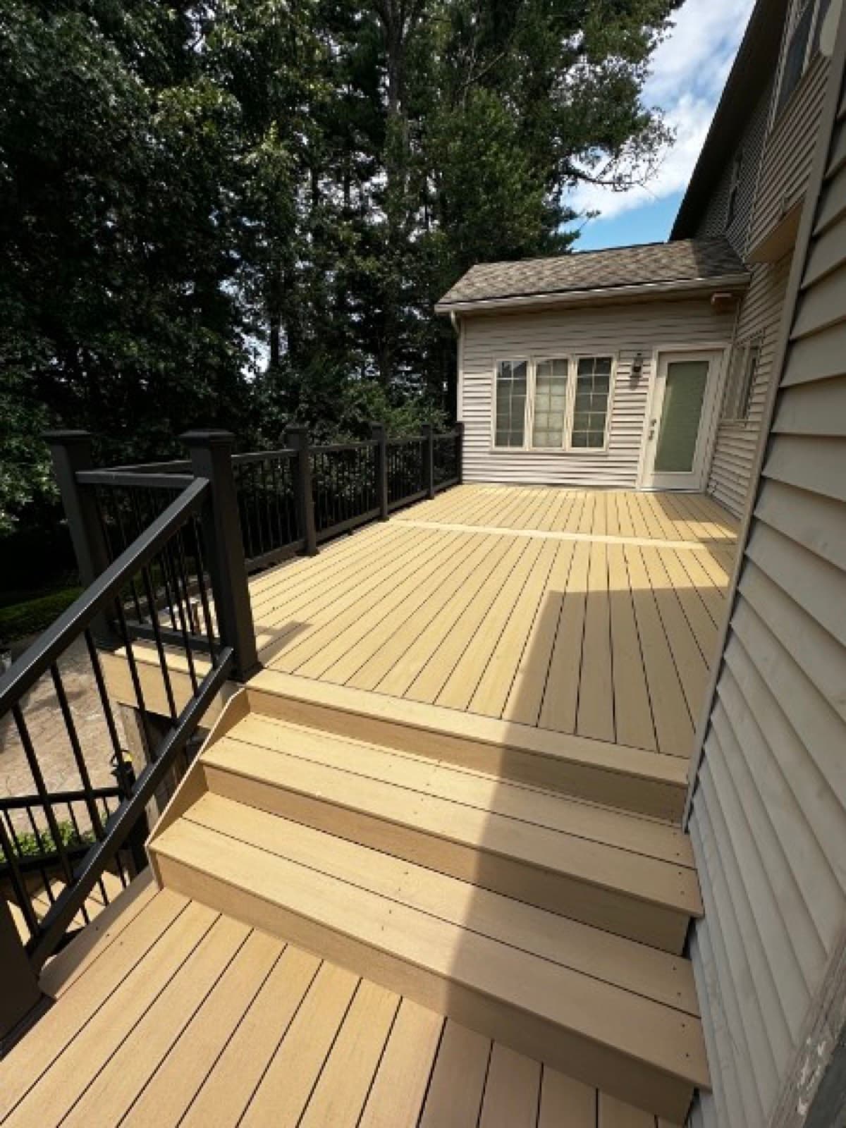 Wide profile of a multi-level composite deck along a two-story home with stair descent