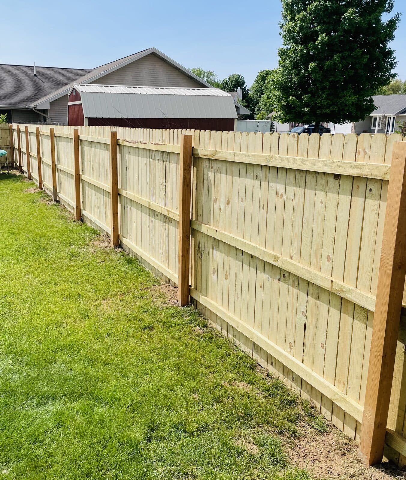 Tall wood privacy fence with shadow-board pattern along grass yard