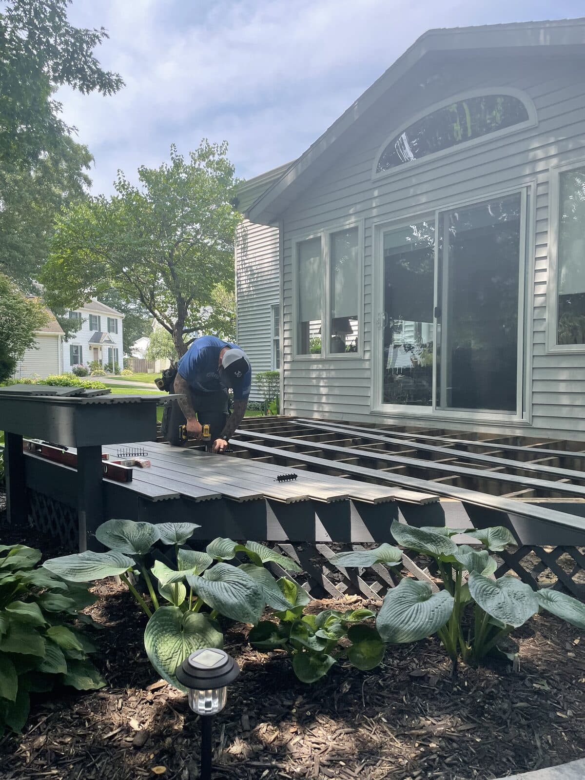 Crew installing new deck in front of the finished home with arched window