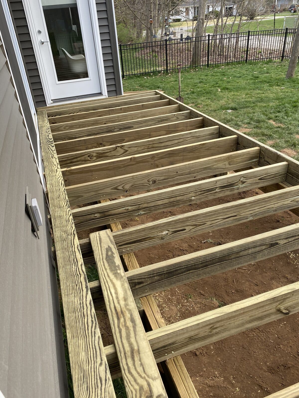 Pressure-treated deck joist frame attached to the home, ready for boards